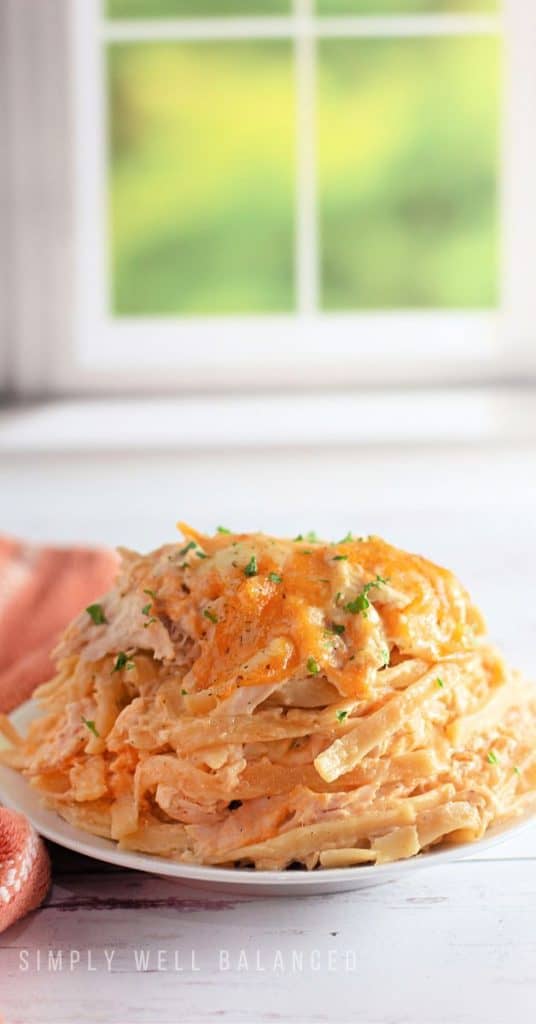 A serving of creamy chicken tetrazzini casserole on a white plate ready to eat. 