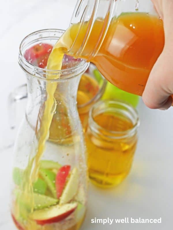 Woman pouring apple pie cider punch into a carafe. 