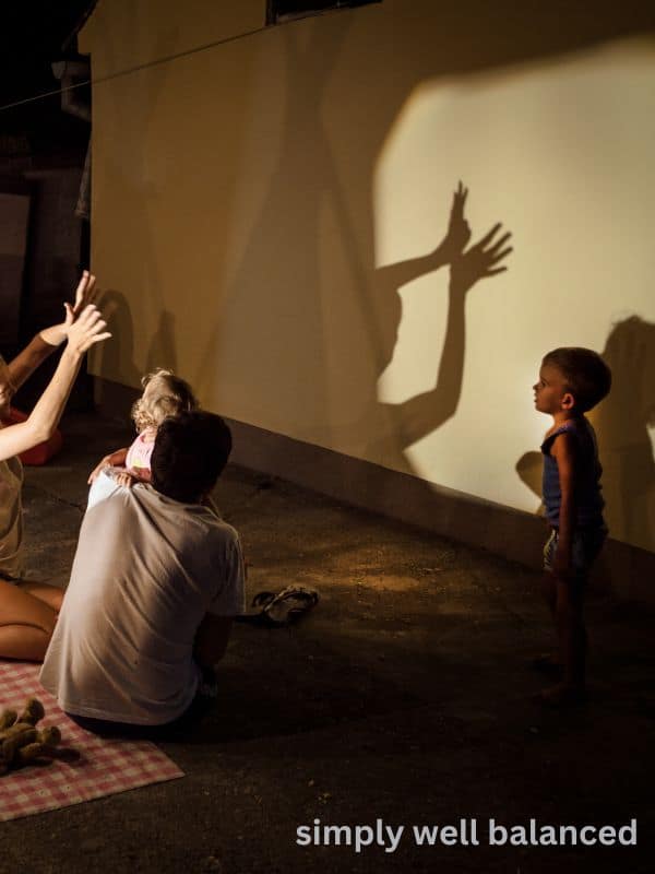 A family making shadow puppets against a wall at night in their backyard. 