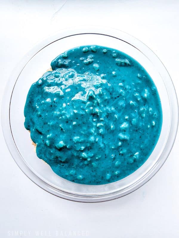 Glass bowl full of rice crispy cereal and covered with blue melted marshamallows. 