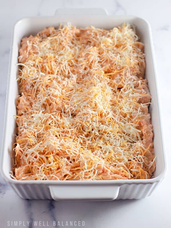 Taco chicken spaghetti, topped with shredded cheese and ready to be baked in the oven. 