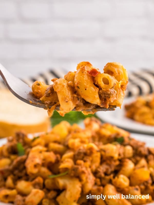 Close up image of cheesy ground beef and zucchini macaroni casserole bake on a fork. 
