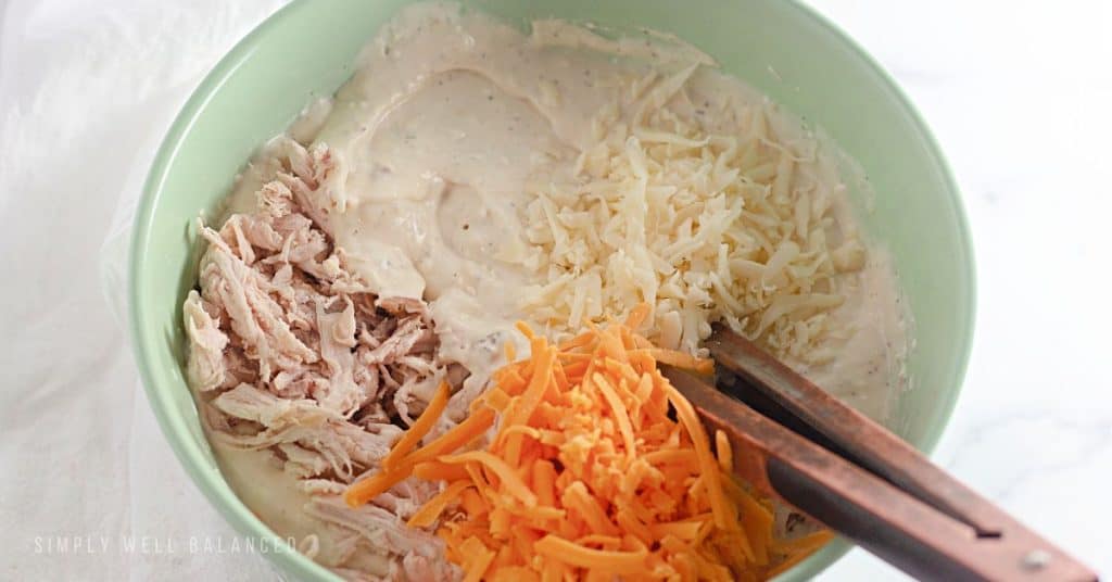 Adding the shredded chicken and shredded cheeses to the chicken tetrazzini sauce. 