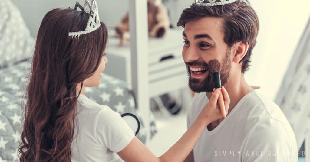 Dad and daughter doing a spa day, putting on makeup and wearing princess crowns. 