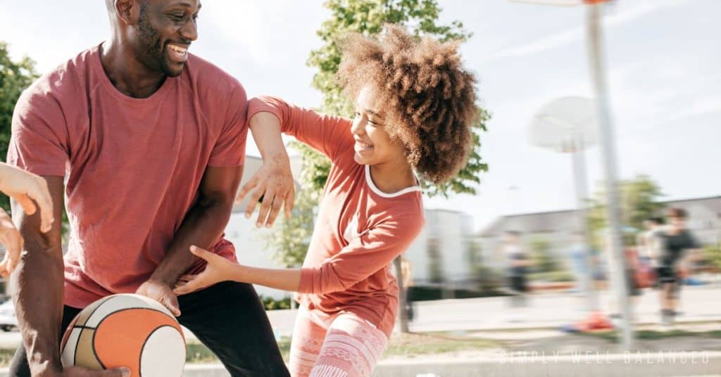 Father and daughter playing basketball together for a daddy daughter date. 
