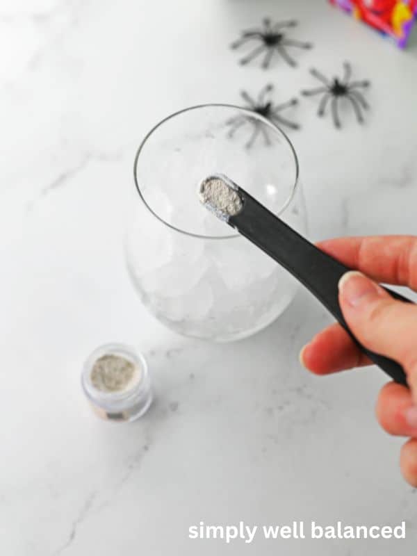 Edible shimmer being added to a glass of non-alcoholic purple punch. 