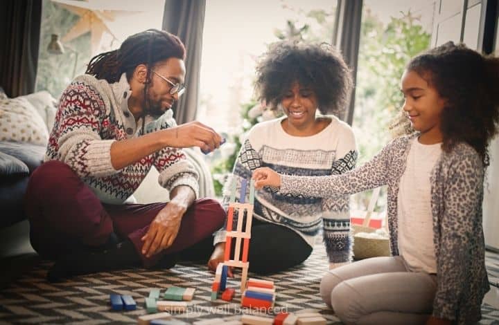 Family playing a game together on living room floor.