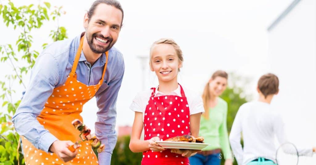 Dad and daughter barbecuing together. 