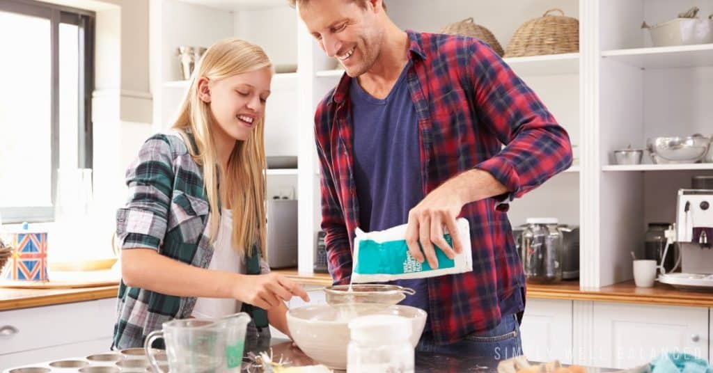 Father and teen daughter cooking together. 
