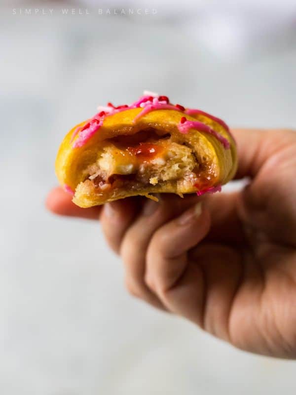Stawberry Crescent Roll with a bite taken out so you can see the filling. 