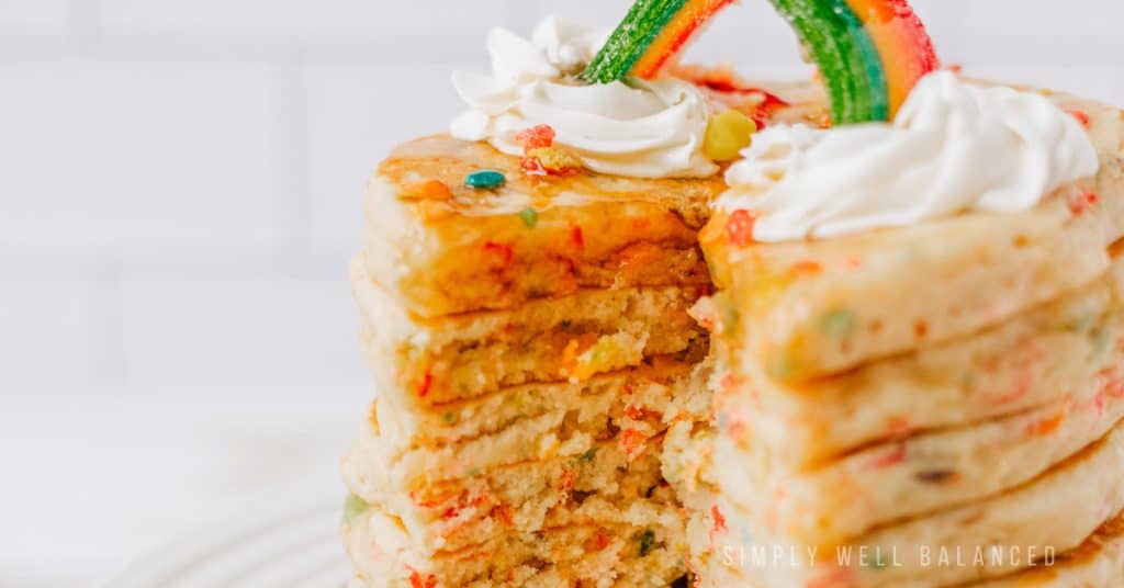 Festive rainbow pancakes made with Fruity Pebble cereal. 
