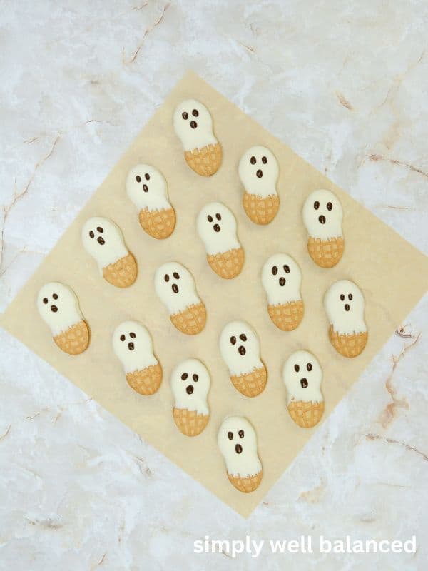 Chocolate eyes and mouth piped onto Nutter Butter ghost cookies. 