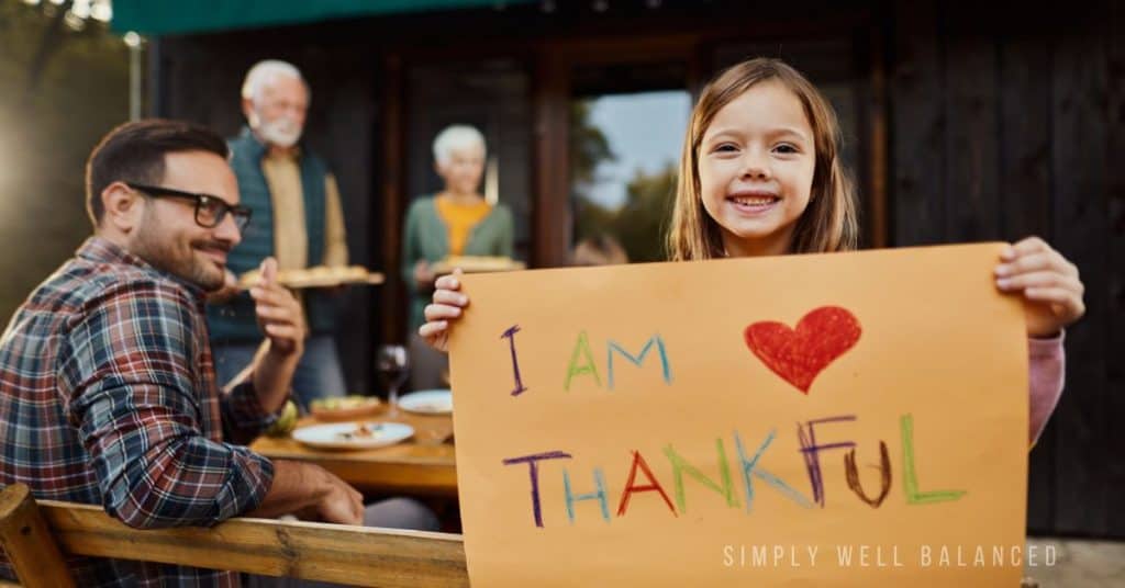 A grateful child showing gratitude with a homemade sign that says I am thankful. 