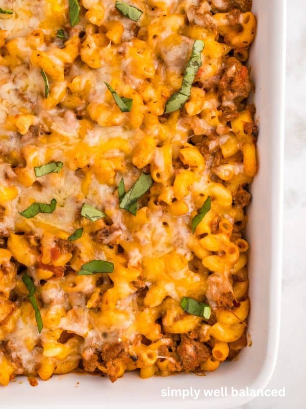 Close up of cheesy beef and zucchini casserole topped with basil. 