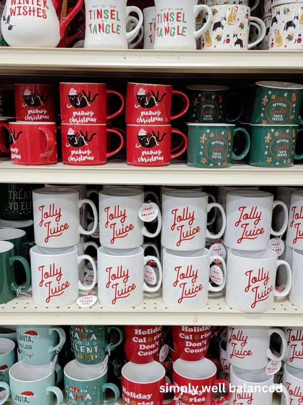 Holiday themed coffee mugs stacked on a store shelf. 