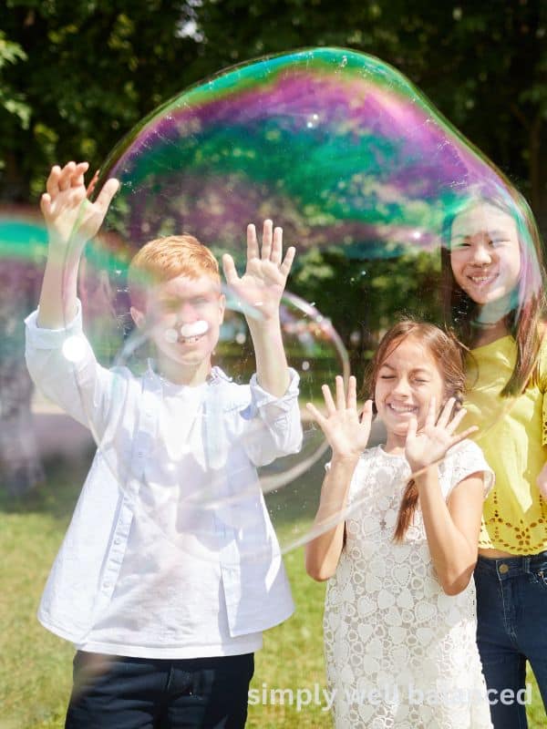 Kids playing with giant homemade bubbles outside.