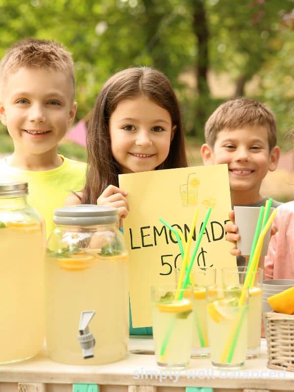 Kids selling lemonade at a lemonade stand during the summer.