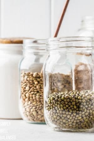 Clear mason jars filled with beans and spices in a minimalist pantry.