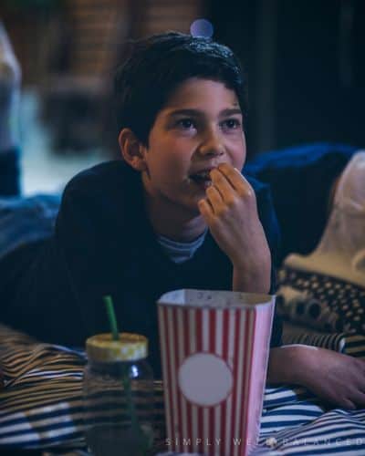 Young boy laying on a blanket watching an outdoor movie at a sleepover. 