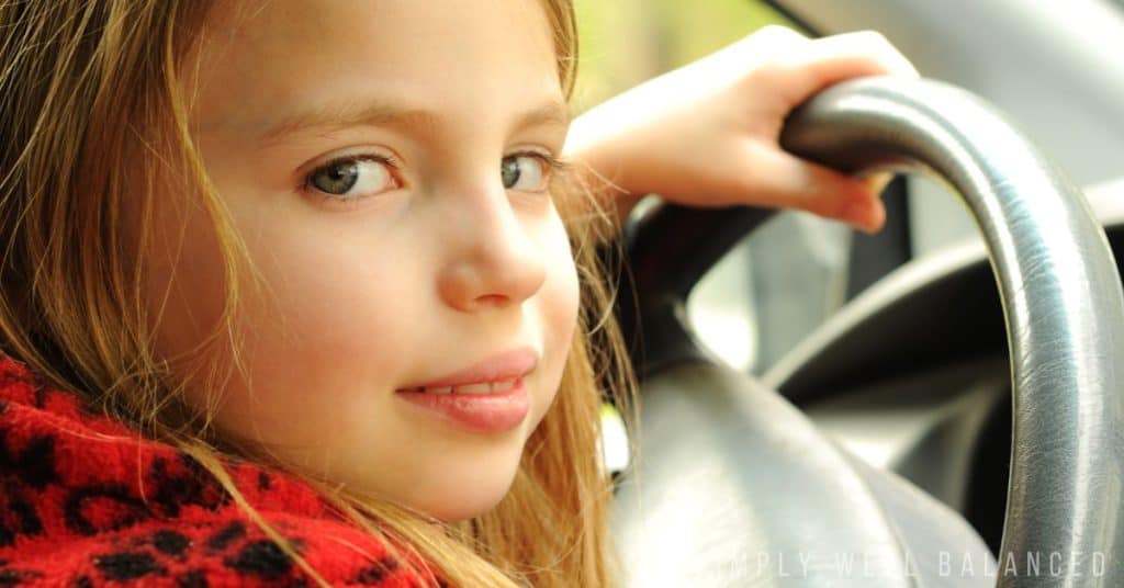A young girl sits behind the wheel of a car. Image text overlay reads "quotes about kids growing up too fast"