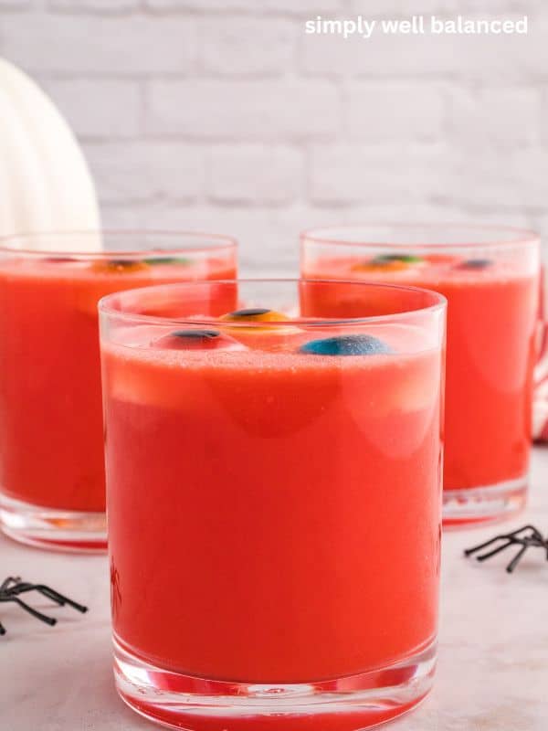 Side view of Red Halloween Punch in a glass with eyeball gummy candies floating to the surface. 