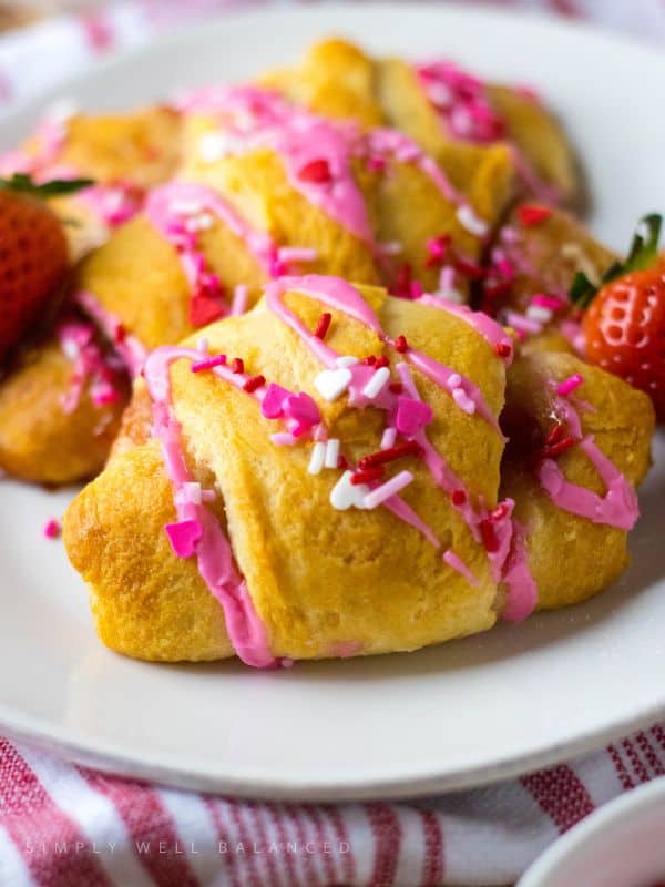 Strawberry cheescake croissants with glaze and sprinkles for Valentine's Day.